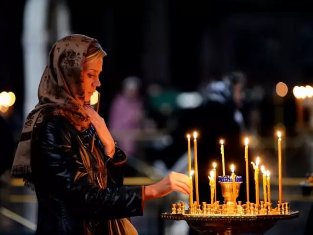 Mergaitė iškelia žvakę į bažnyčią