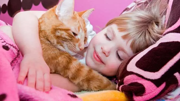 Bērns guļ ar kaķi